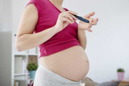 Беременная девушка использует глюкометр
